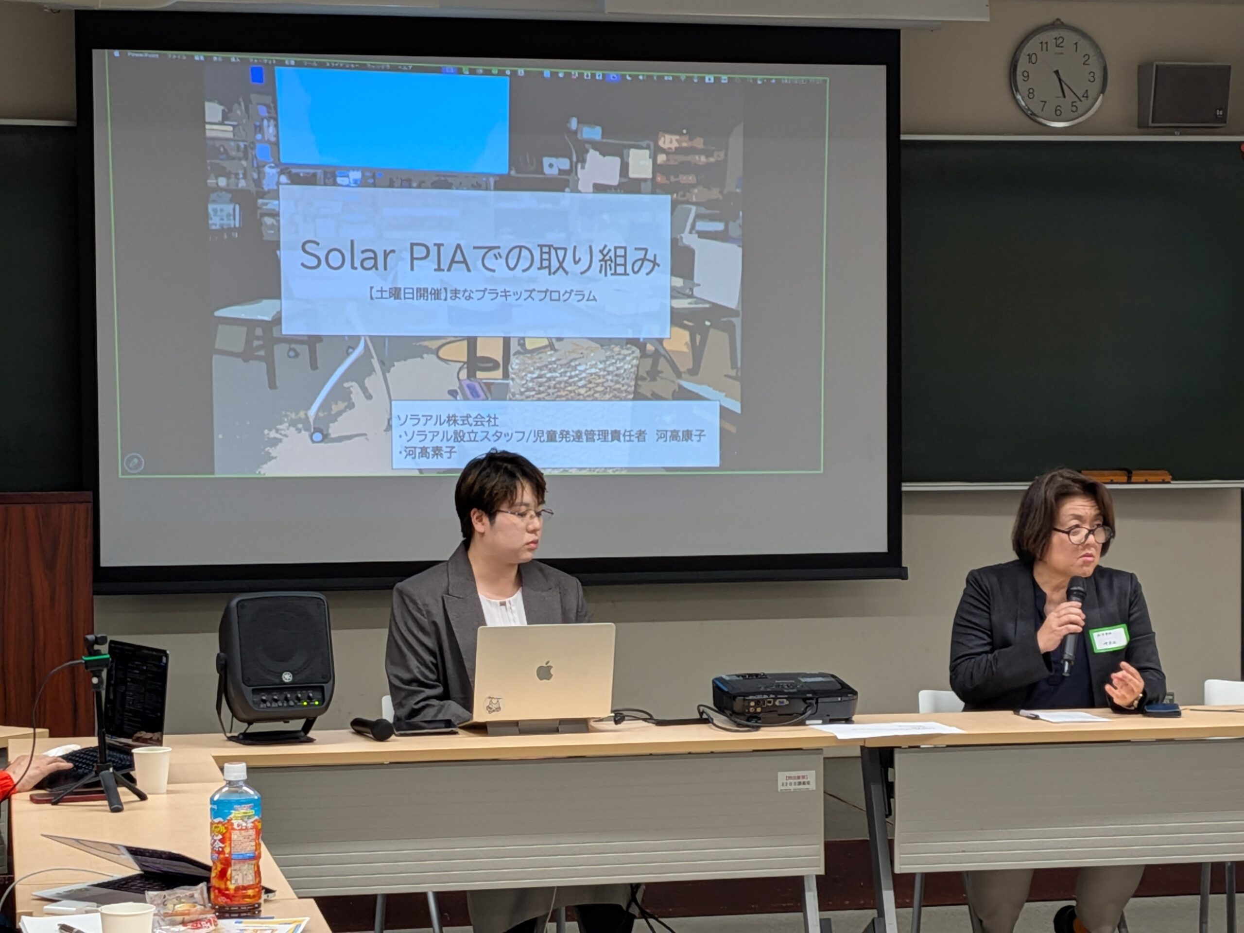 ソラアルPIAの実践報告。スクリーンに「Solar PIAでの取り組み」のスライドが映し出され、2名の登壇者が発表している