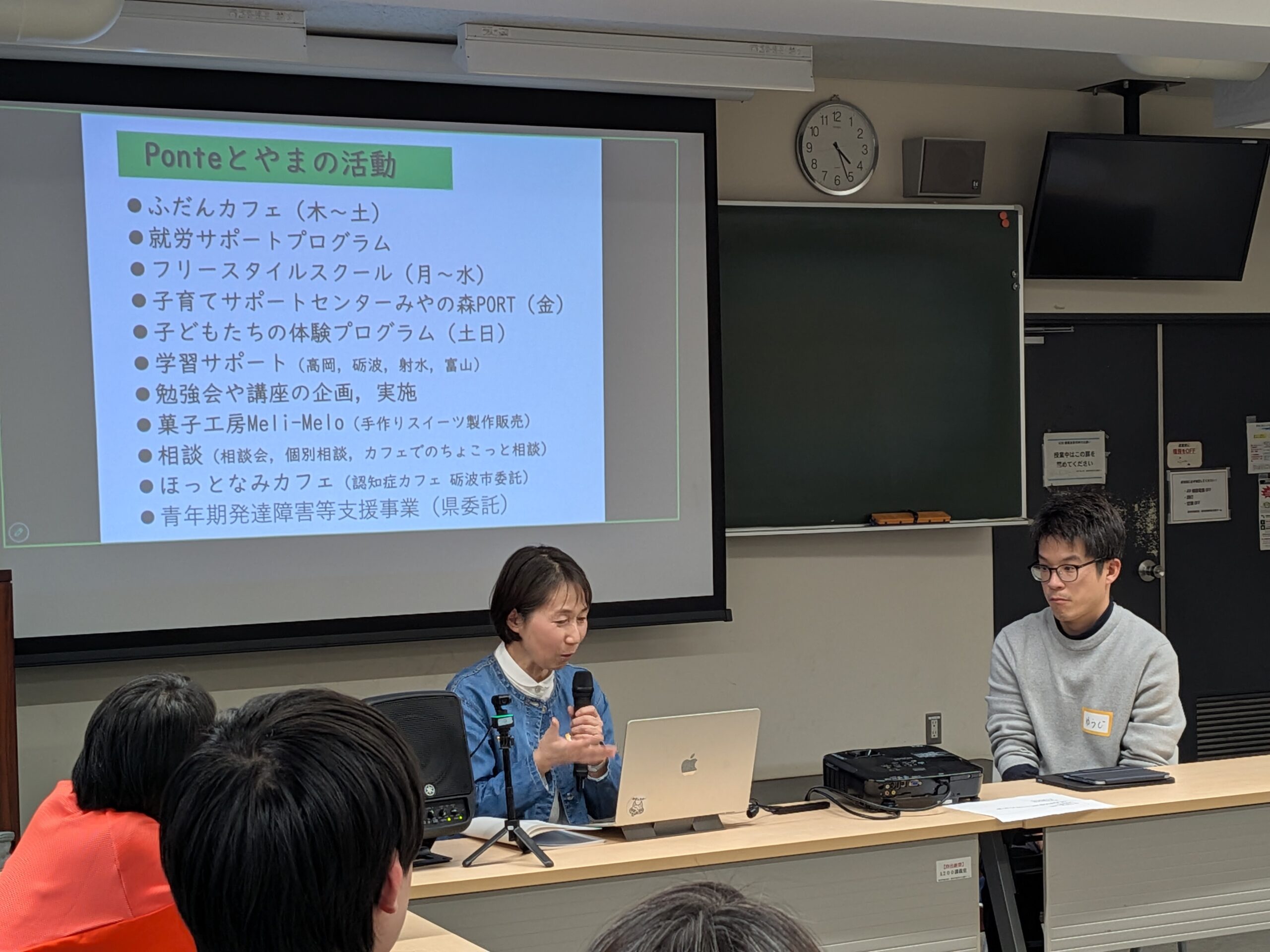 Ponteとやまの実践報告。スクリーンに活動内容が映し出され、登壇者がマイクを持って説明している